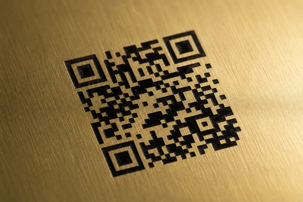 Gros plan sur un QR code gravé au laser dans le laiton brossé d'une plaque souvenir